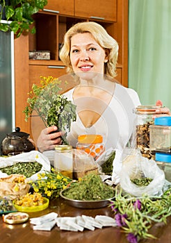 Mature woman sitting at table with medicinal herbs