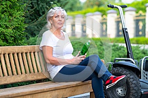 Mature woman sitting on wooden bench in summer