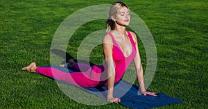 mature woman in sportswear stretching body on fitness mat at public park, doing yoga. Young active woman. Healthy