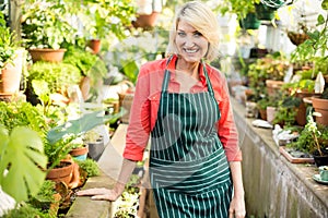 Mature woman standing amidst plants at greenhouse