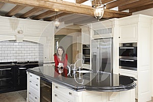 Mature Woman Standing In New Luxury Fitted Kitchen photo