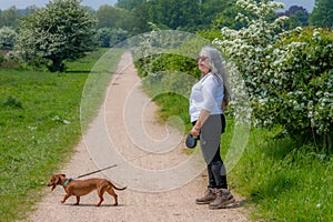 Mature woman standing next to her dog on hiking trail