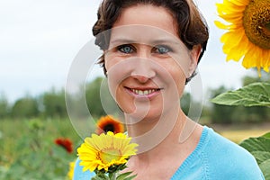 Mature woman standing in a sunflower field photo