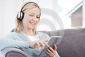 Mature Woman Streams Music From Digital Tablet To Wireless Headphones