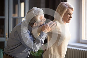 Mature woman suffering from sudden backache, old man supporting her