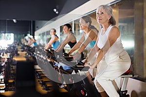 Mature woman taking cycling class at gym