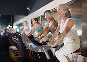 Mature woman taking cycling class at gym