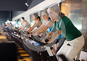 Mature woman taking cycling class at gym