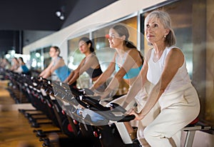 Mature woman taking cycling class at gym