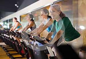 Mature woman taking cycling class at gym