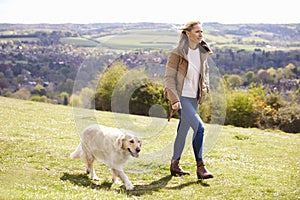Mature Woman Taking Golden Retriever For Walk In Countryside