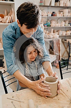 Mature woman teaching boy to make clay crafts at pottery workshop