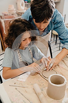 Mature woman teaching boy to make clay crafts at workshop
