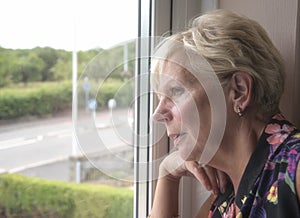 Mature woman thinking and looking out of a window