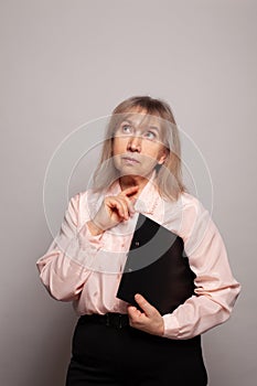Mature woman thinking and looking up on gray background