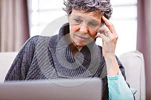 Mature woman thinking while using laptop