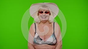 Mature woman traveler on vacation in red sunglasses, looking at camera, smiling, starting laughing