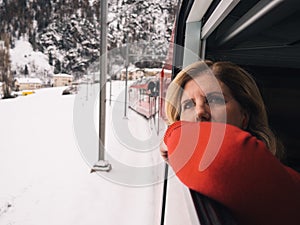 Mature woman traveling by train in winter snowy landscape looking out the window