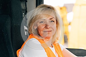 Mature woman truck driver steering wheel inside lorry cabin. Happy middle age female trucker portrait