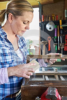 Mature Woman Upcycling Furniture In Workshop At Home