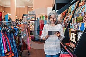 Mature woman using a digital tablet in her textiles shop