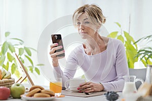 Mature woman using her smartphone at home
