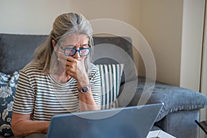 mature woman using laptop at home with a doubtful gesture