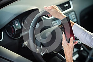 Mature woman using a smart phone while driving a car