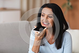 Mature woman using voice assistant on her smartphone