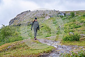 Mature woman walks down in high altitude Norwegian Mountains range terrain. Hiking high in Norwegian mountains. Healthy lifestyle