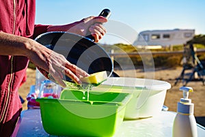 Woman washing dishes in bowl, capming outdoor photo