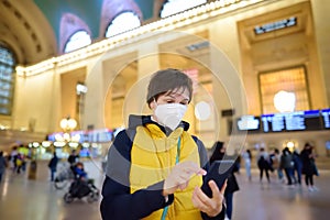 Mature woman wearing a face mask is using her phone to buy a ticket online in Grand Central Station New York, Manhattan. Female photo