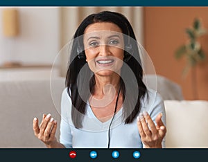 Mature Woman Wearing Headset Having Video Conference photo