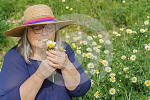 mature woman with white hair and hat holding a bouquet of daisies in her hands