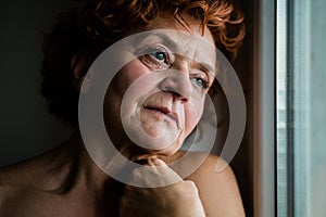 Mature woman by the window thinking about life