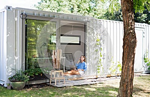 Mature woman working in home office in container house in backyard.