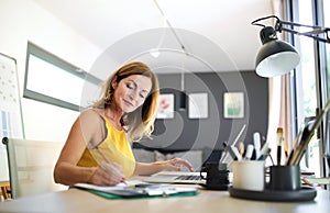 Mature woman working indoors in home office in container house in backyard.