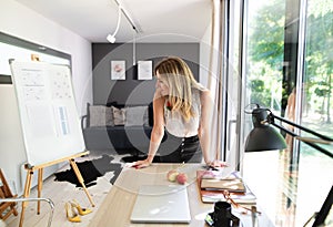 Mature woman working indoors in home office in container house in backyard.