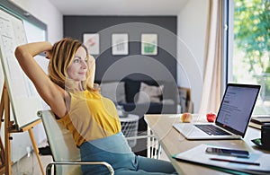 Mature woman working indoors in home office in container house in backyard, resting.