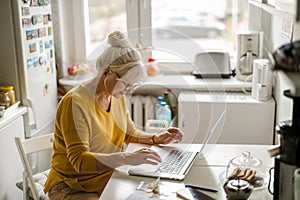 Mature woman working on laptop in kitchen