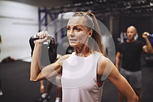 Mature woman working out with weights in a gym class