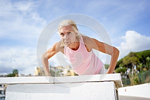 Mature woman working strength training push ups against sky with copyspace.