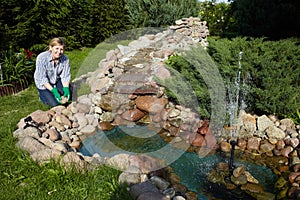 Mature woman works around pond in her garden