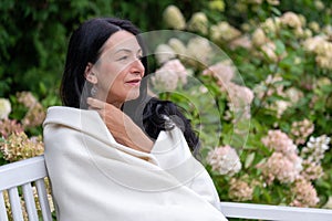 A mature woman, wrapped warmly, gazes into the distance, her expression one of peaceful self-acceptance during the life