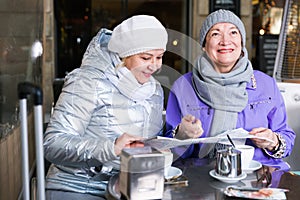 Mature women with city guide at terrace cafe