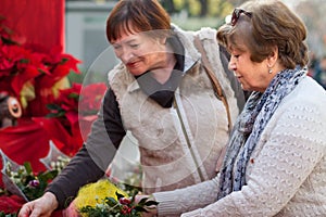 mature women considering decorations at Christmas market