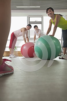 mature women exercising with fitness ball and looking at the trainer