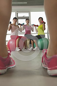 mature women exercising with fitness ball and looking at the trainer