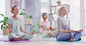 Mature women meditating in lotus pose with mudra hand gesture during a fitness class in a yoga studio. Calm, relaxed and