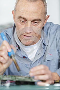 Mature worker soldering pc parts